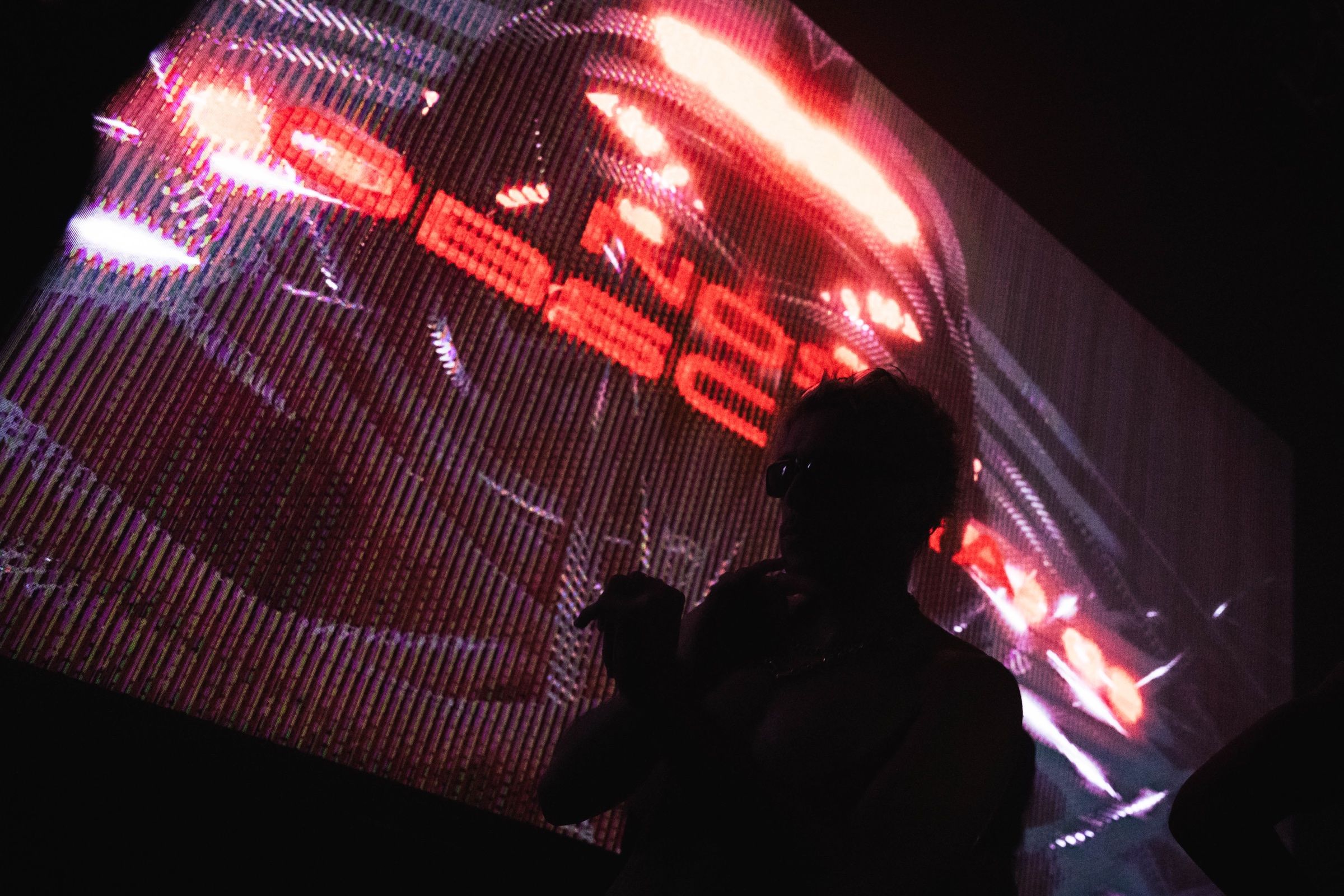 A silhouette in front of a large screen showing NOS OBSCURA